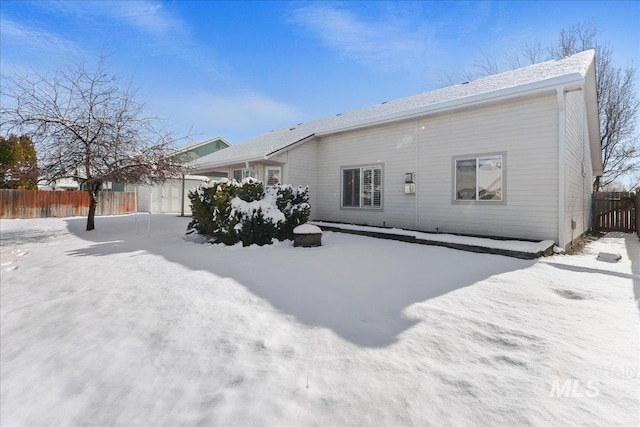 snow covered back of property featuring fence