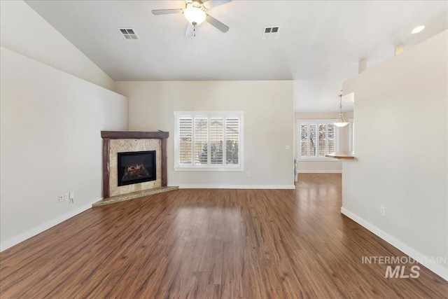 unfurnished living room with baseboards, visible vents, ceiling fan, a premium fireplace, and wood finished floors