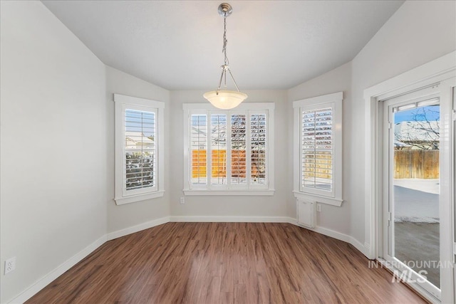 unfurnished dining area with lofted ceiling, baseboards, and wood finished floors