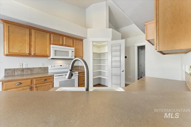 kitchen featuring lofted ceiling, white appliances, light countertops, and a sink