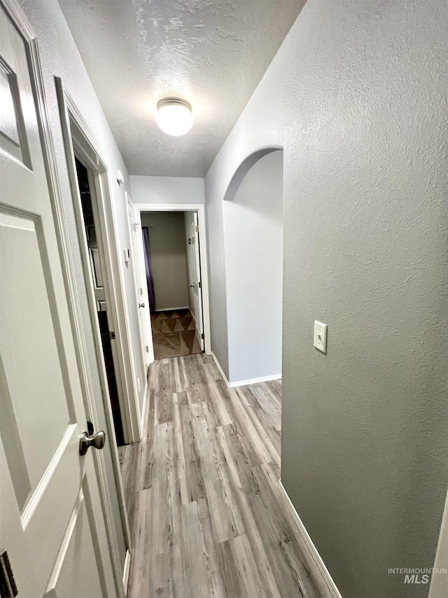 981 SW Independence, Mountain Home, ID 83647 - hall with a textured ceiling, a textured wall, baseboards, and light wood finished floors
