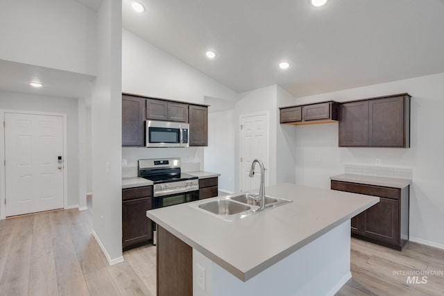 kitchen with light hardwood / wood-style floors, a kitchen island with sink, sink, and stainless steel appliances