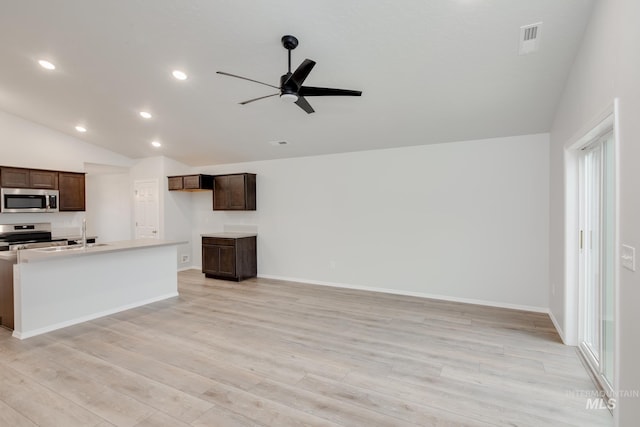 kitchen featuring stainless steel appliances, light wood-type flooring, lofted ceiling, ceiling fan, and plenty of natural light