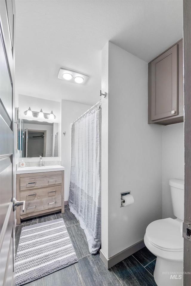 946 S Curtis Rd, Boise, ID 83705 - full bathroom featuring toilet, vanity, wood finish floors, curtained shower, and baseboards