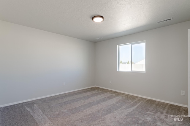 carpeted empty room with a textured ceiling