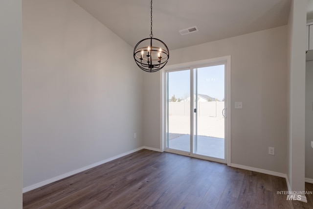 empty room with dark hardwood / wood-style floors and an inviting chandelier