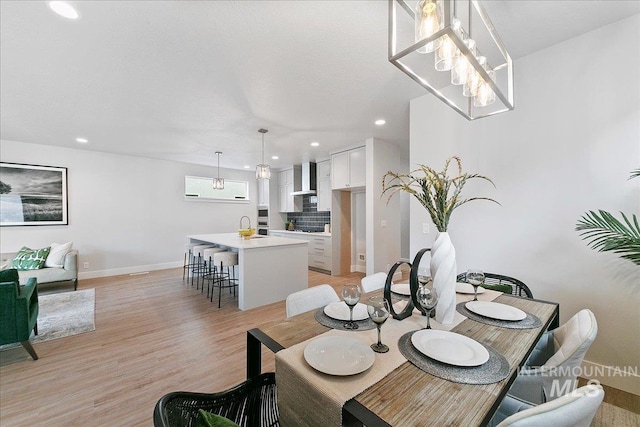 dining area featuring a notable chandelier, sink, and light hardwood / wood-style flooring