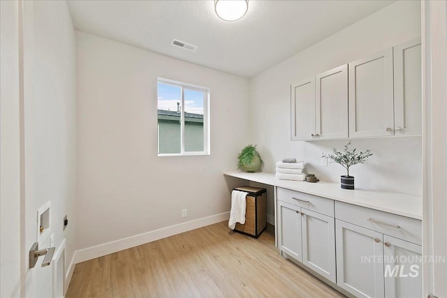 clothes washing area featuring cabinets, light hardwood / wood-style floors, and hookup for an electric dryer