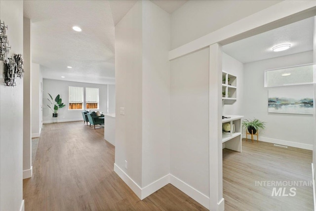 hall featuring a textured ceiling and light hardwood / wood-style flooring