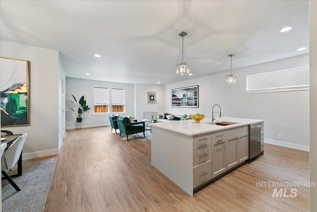 kitchen featuring dishwasher, a kitchen island with sink, sink, hanging light fixtures, and gray cabinets