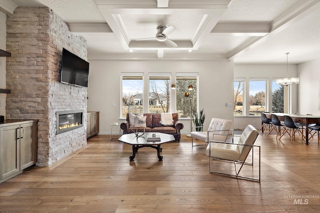 living room with coffered ceiling, a stone fireplace, beamed ceiling, and light wood-type flooring