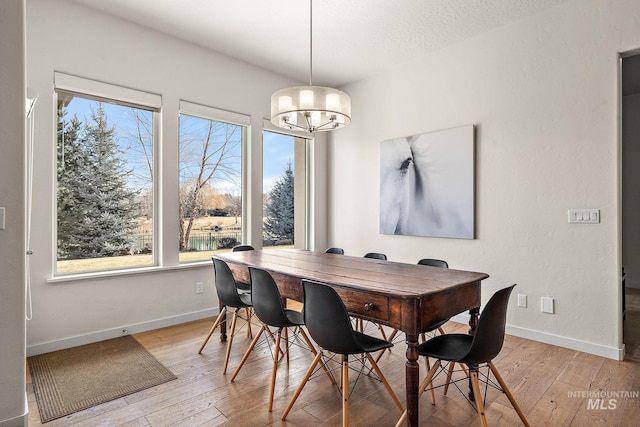 dining space with a textured ceiling, light hardwood / wood-style flooring, and a notable chandelier