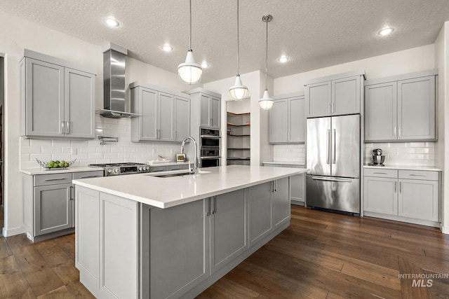 kitchen featuring decorative light fixtures, sink, gray cabinetry, stainless steel appliances, and wall chimney range hood