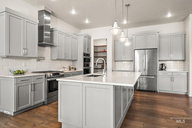 kitchen with wall chimney exhaust hood, appliances with stainless steel finishes, dark hardwood / wood-style floors, and gray cabinetry