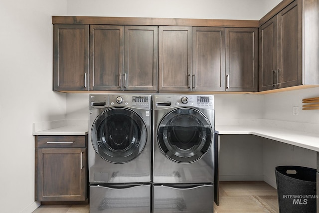 clothes washing area featuring separate washer and dryer and cabinets