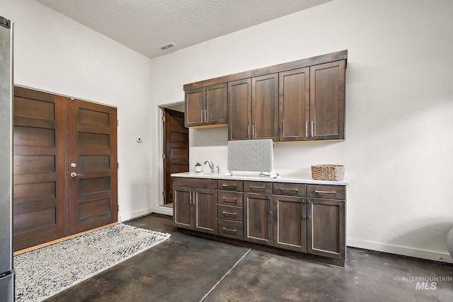 kitchen featuring dark brown cabinetry, sink, and a textured ceiling