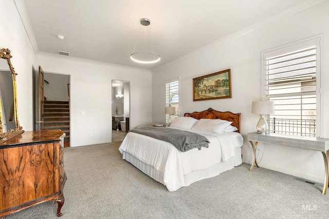 carpeted bedroom with ornamental molding and connected bathroom