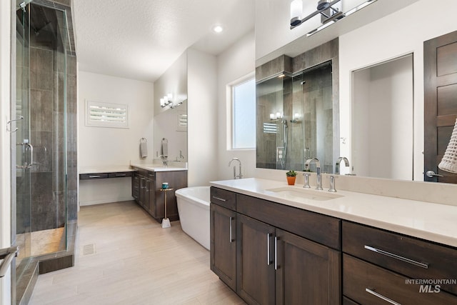 bathroom with independent shower and bath, vanity, hardwood / wood-style flooring, and a textured ceiling