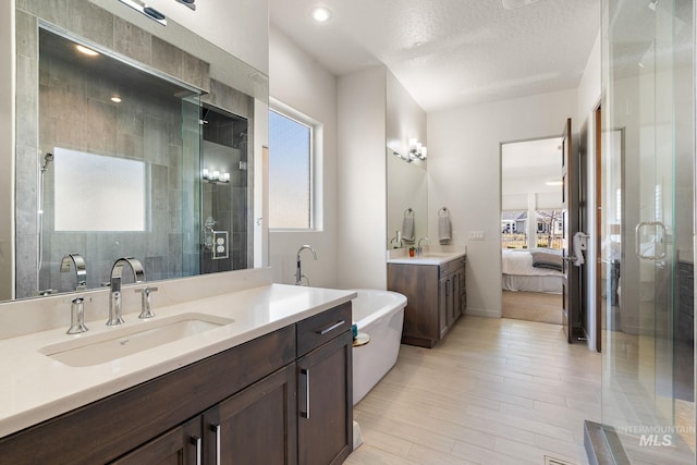 bathroom featuring vanity, separate shower and tub, a wealth of natural light, and a textured ceiling