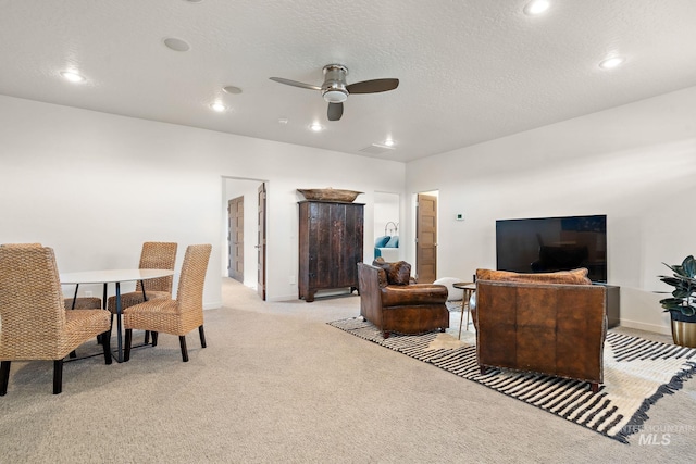 living room with ceiling fan, light colored carpet, and a textured ceiling