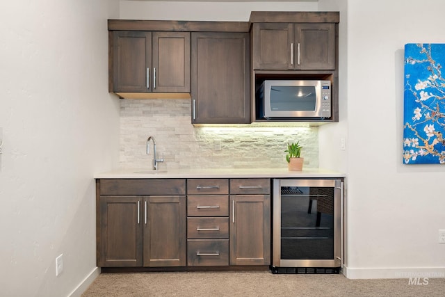 bar with wine cooler, sink, decorative backsplash, and dark brown cabinetry