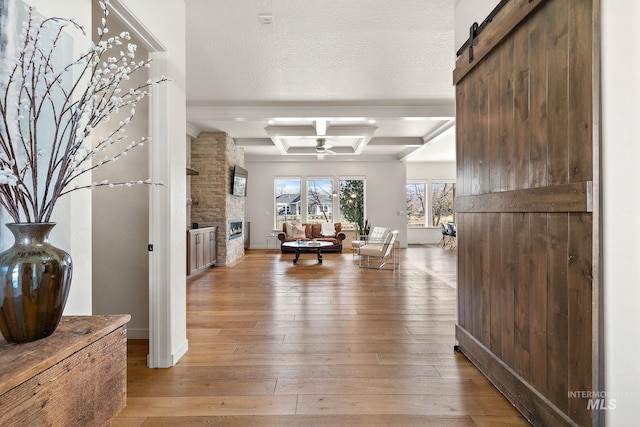 hallway featuring wood-type flooring, beam ceiling, coffered ceiling, a barn door, and a textured ceiling