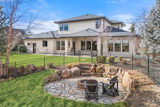 back of house featuring a lawn, a patio, and an outdoor fire pit