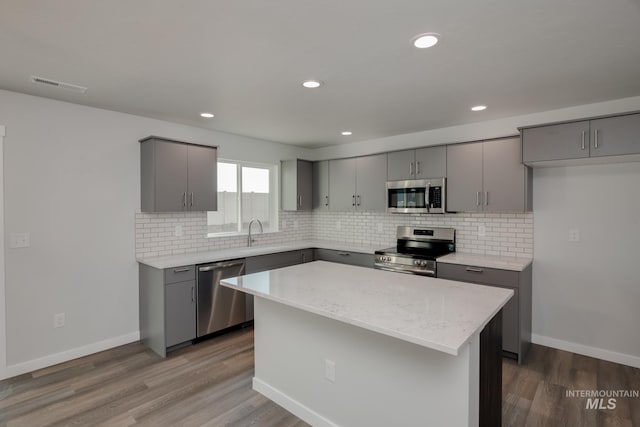 kitchen with gray cabinets, a center island, light wood-type flooring, and appliances with stainless steel finishes