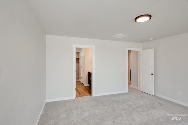 unfurnished bedroom featuring connected bathroom, a spacious closet, and light colored carpet