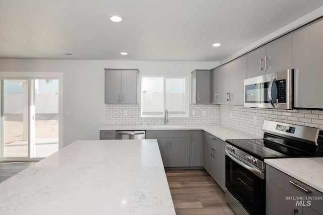 kitchen featuring appliances with stainless steel finishes, gray cabinets, and hardwood / wood-style floors