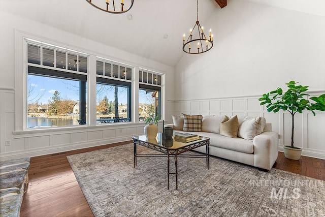 living room featuring beam ceiling, high vaulted ceiling, a water view, a notable chandelier, and wood-type flooring