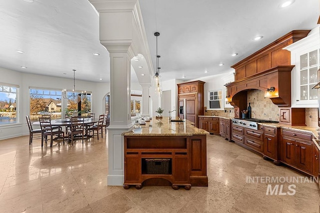 kitchen with ornate columns, tasteful backsplash, hanging light fixtures, paneled refrigerator, and stainless steel gas stovetop