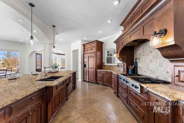 kitchen with pendant lighting, sink, paneled built in refrigerator, stainless steel gas cooktop, and light stone counters