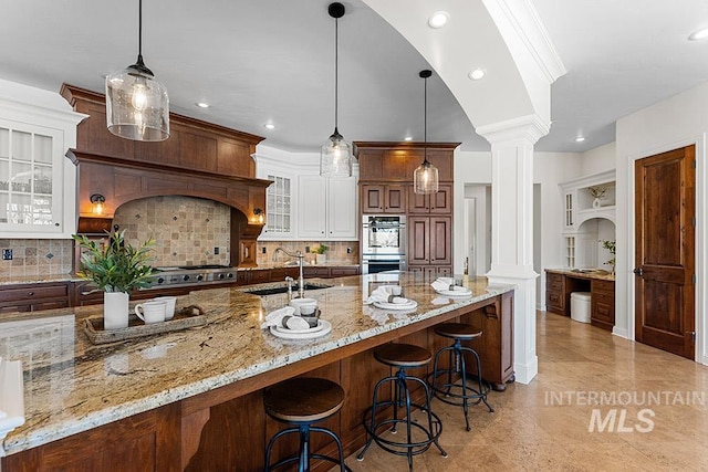 kitchen featuring pendant lighting, decorative columns, and white cabinets