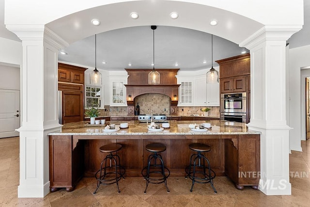 kitchen with pendant lighting, white cabinetry, and decorative columns