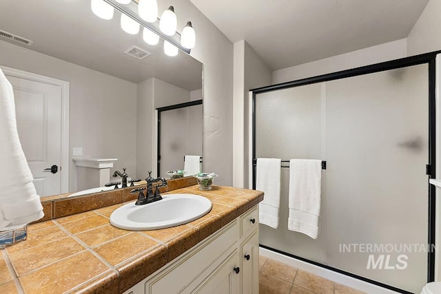 bathroom with an enclosed shower, vanity, and tile patterned flooring