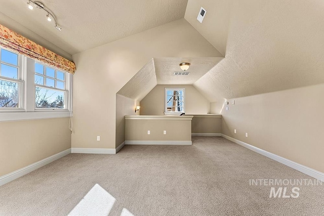 bonus room featuring lofted ceiling, light carpet, and a textured ceiling