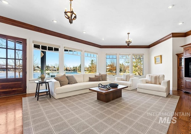 living room featuring a water view, ornamental molding, a chandelier, and light hardwood / wood-style floors