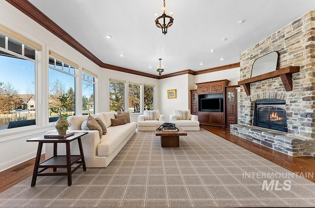 living room with a notable chandelier, hardwood / wood-style floors, a stone fireplace, and ornamental molding