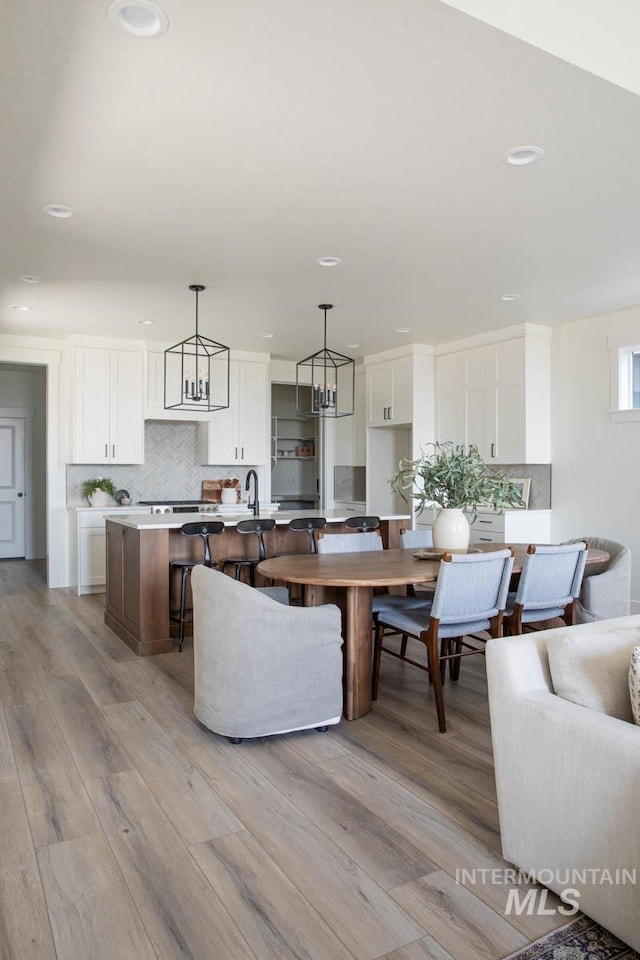 6104 S Apex Ave, Meridian, ID 83642 - kitchen with tasteful backsplash, white cabinetry, light wood-style floors, a kitchen island, and recessed lighting