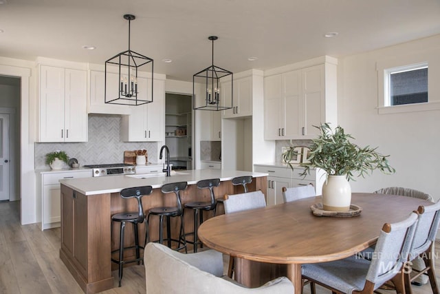 6104 S Apex Ave, Meridian, ID 83642 - kitchen featuring a kitchen island with sink, light wood-type flooring, white cabinets, backsplash, and recessed lighting