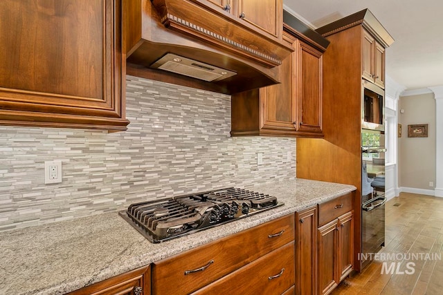 kitchen featuring light hardwood / wood-style flooring, custom range hood, appliances with stainless steel finishes, and tasteful backsplash