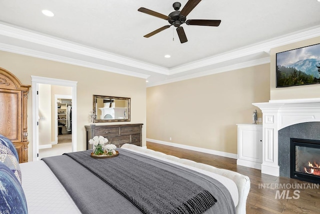 bedroom featuring hardwood / wood-style floors, ceiling fan, a raised ceiling, and crown molding