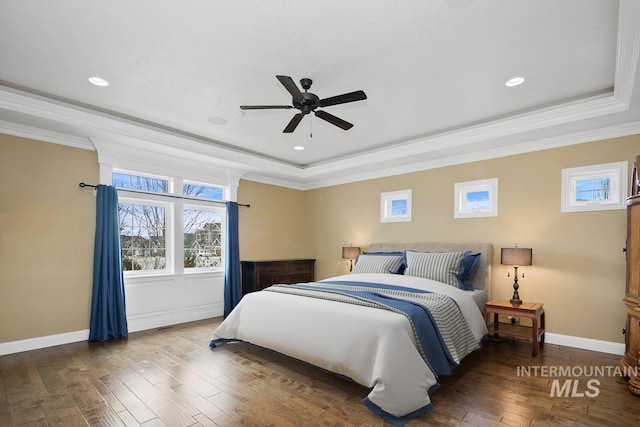 bedroom featuring dark wood-type flooring, ceiling fan, a raised ceiling, and ornamental molding