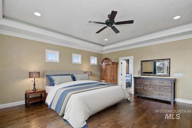 bedroom with dark hardwood / wood-style floors, a raised ceiling, ceiling fan, connected bathroom, and ornamental molding