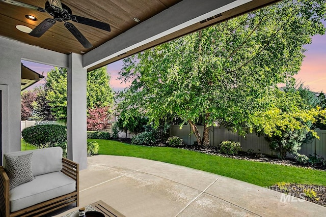 patio terrace at dusk with ceiling fan and a lawn