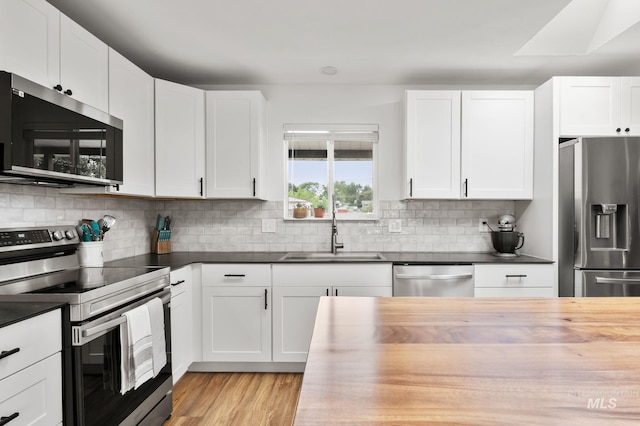 3513 7th St E, Lewiston, ID 83501 - kitchen with appliances with stainless steel finishes, backsplash, wood counters, white cabinetry, and light wood-style flooring