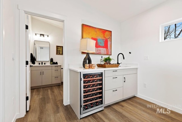 bar featuring beverage cooler, sink, and hardwood / wood-style floors