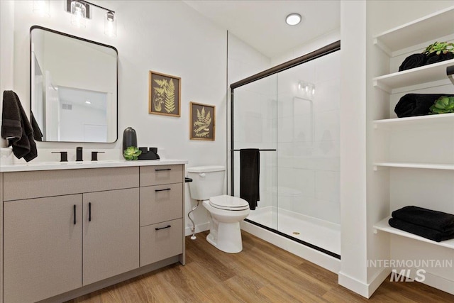 bathroom with wood-type flooring, toilet, vanity, and a shower with shower door