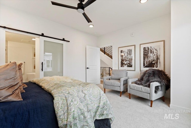 bedroom with ensuite bathroom, a barn door, ceiling fan, and carpet flooring